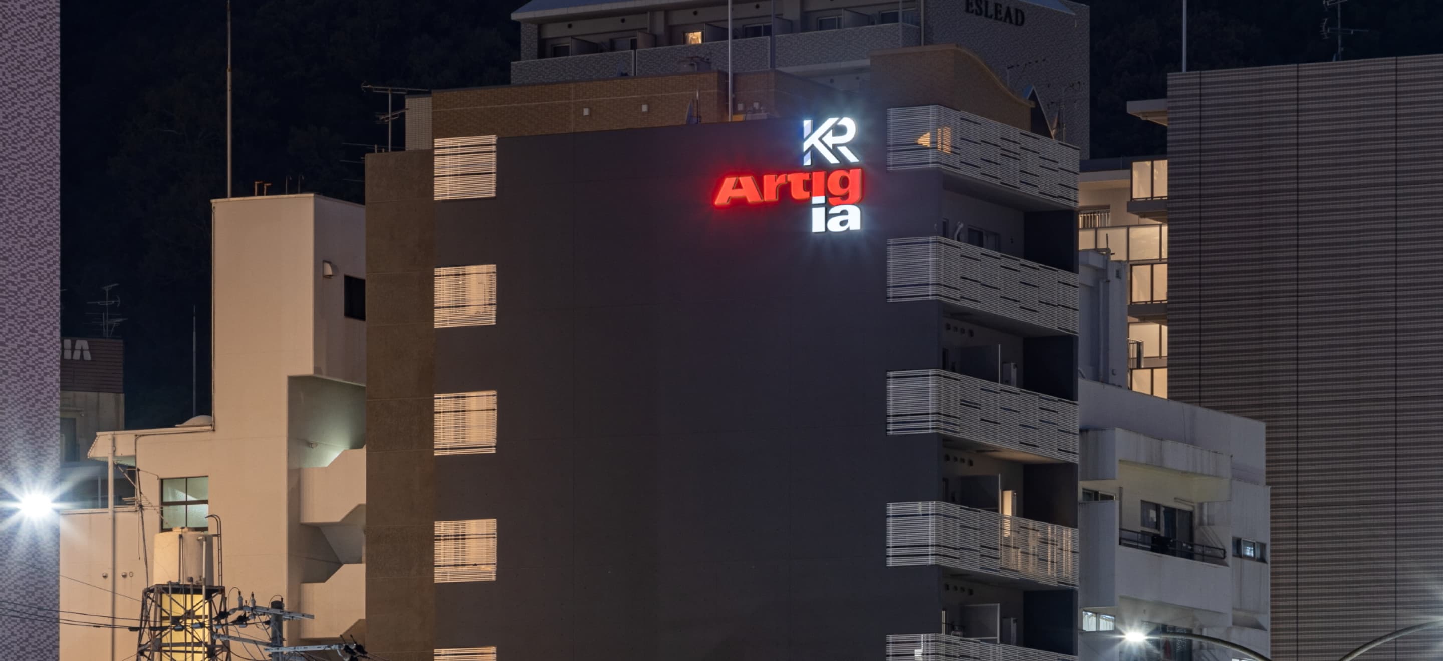 夜に光るKRとArtigliaのロゴが見えるK・R三宮イースト外観